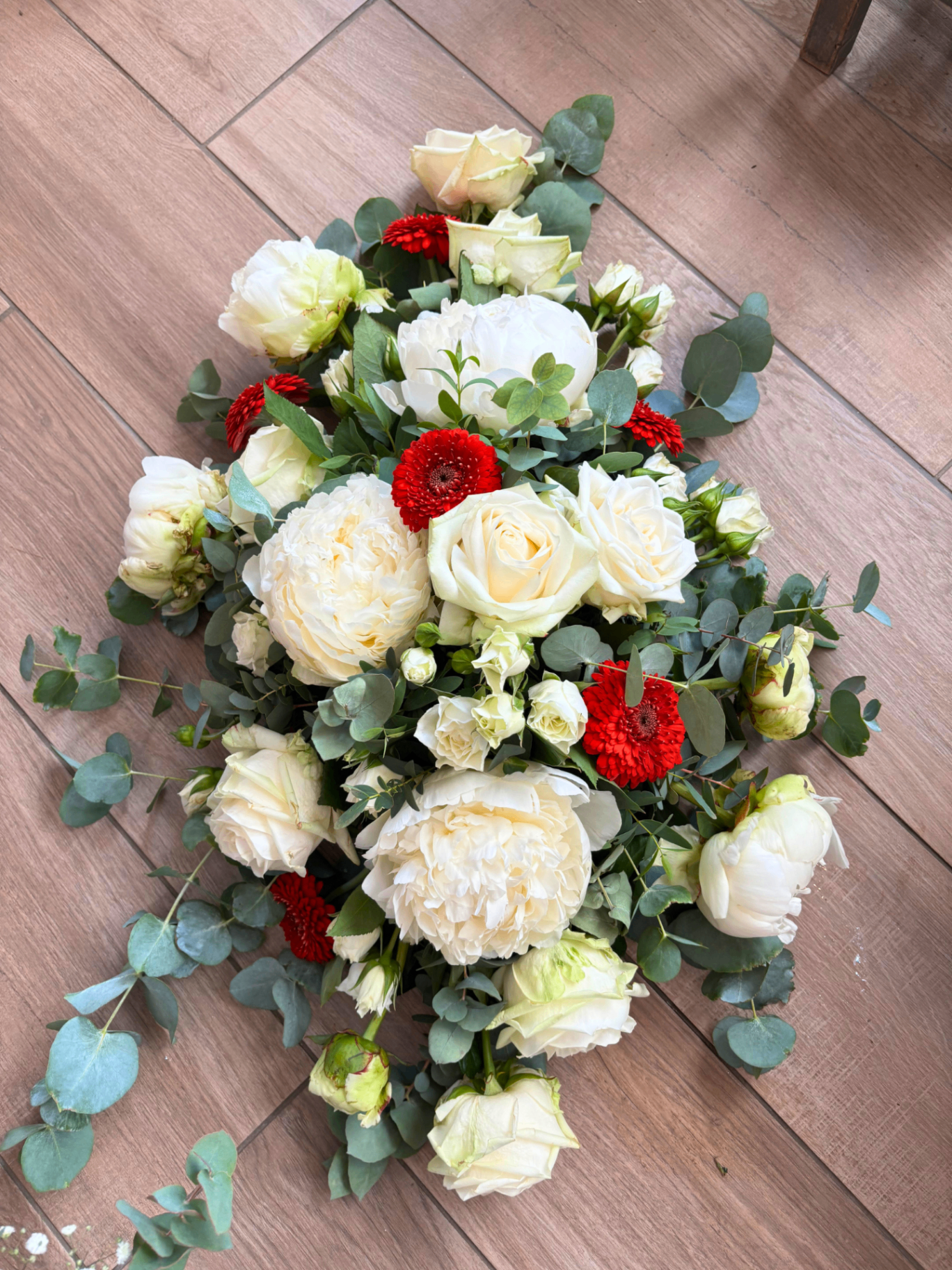 Composition nuptiale blanche et rouge avec pivoines, roses et eucalyptus